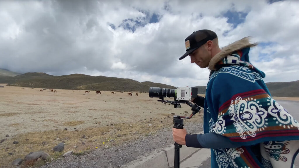An image of a man standing in the desert using a camera on a stand