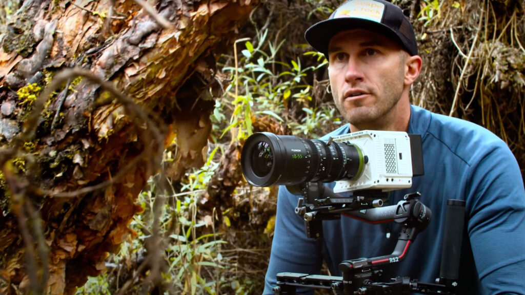 An image of a man wearing a hat behind a camera